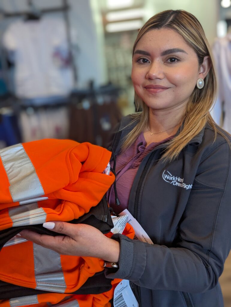Erica holding high-visibility safety apparel inside the Work Hard Dress Right store in Newark.