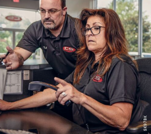 Office staff wearing coordinated branded polos collaborate at a workstation.