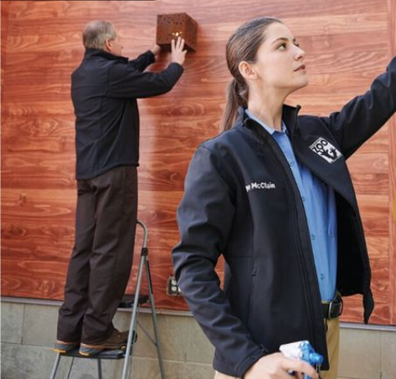 Field service employees wearing branded jackets and work shirts while performing an installation task.