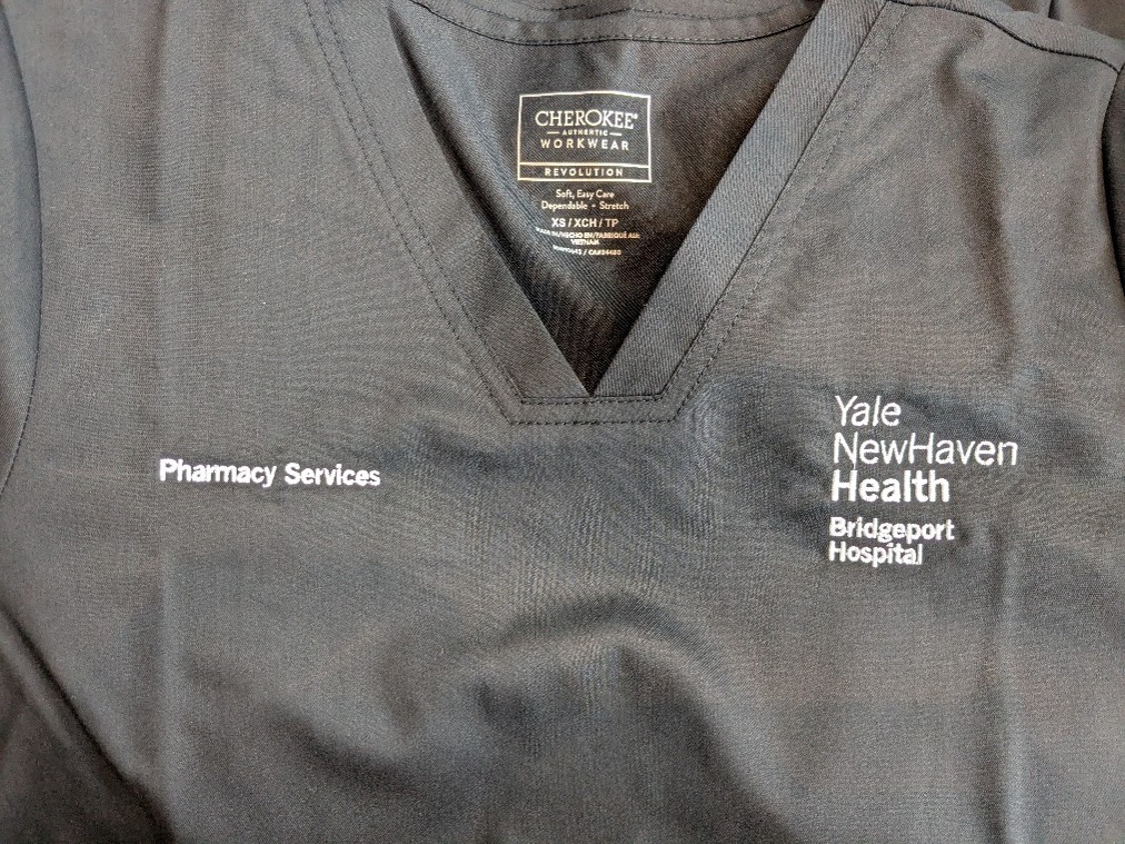 Customized healthcare scrub top with embroidered hospital branding and Pharmacy Services department identification.